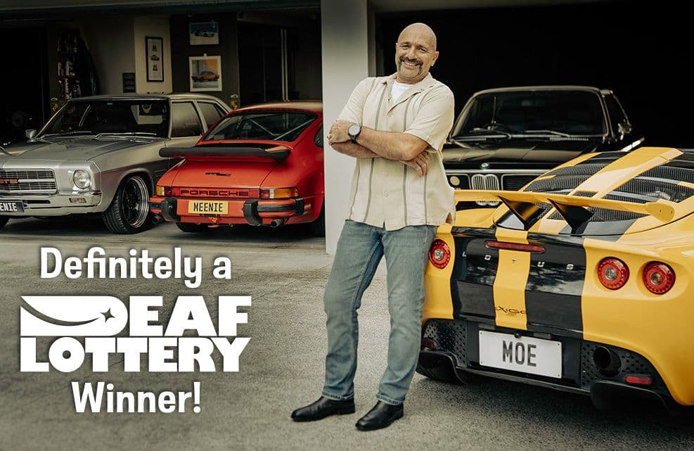 Deaf Lottery campaign creative: a man among cars, with the new identity and the line ‘Definitely a Deaf Lottery Winner!’