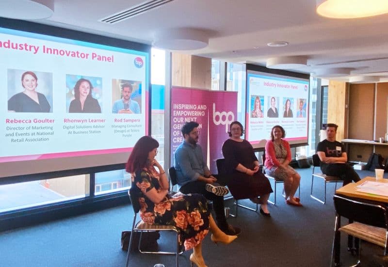 Bec seated on the Industry Innovator Panel, with her name visible on the presentation slide